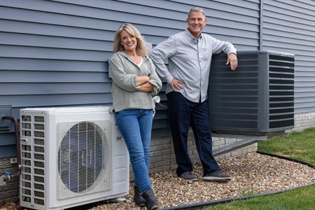 Pete and Megan standing next to an air conditioner