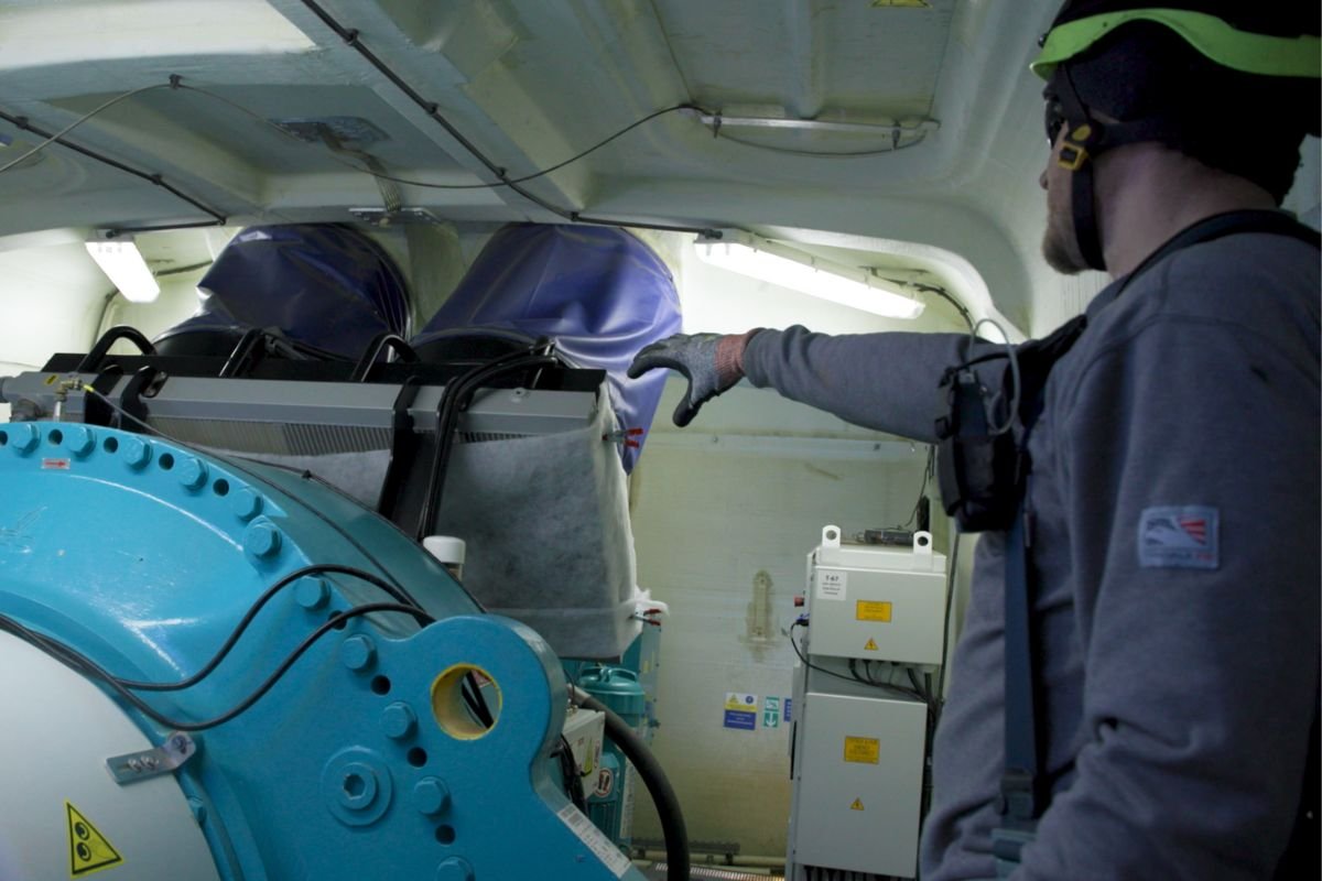Wind technician inspecting parts inside turbine. 