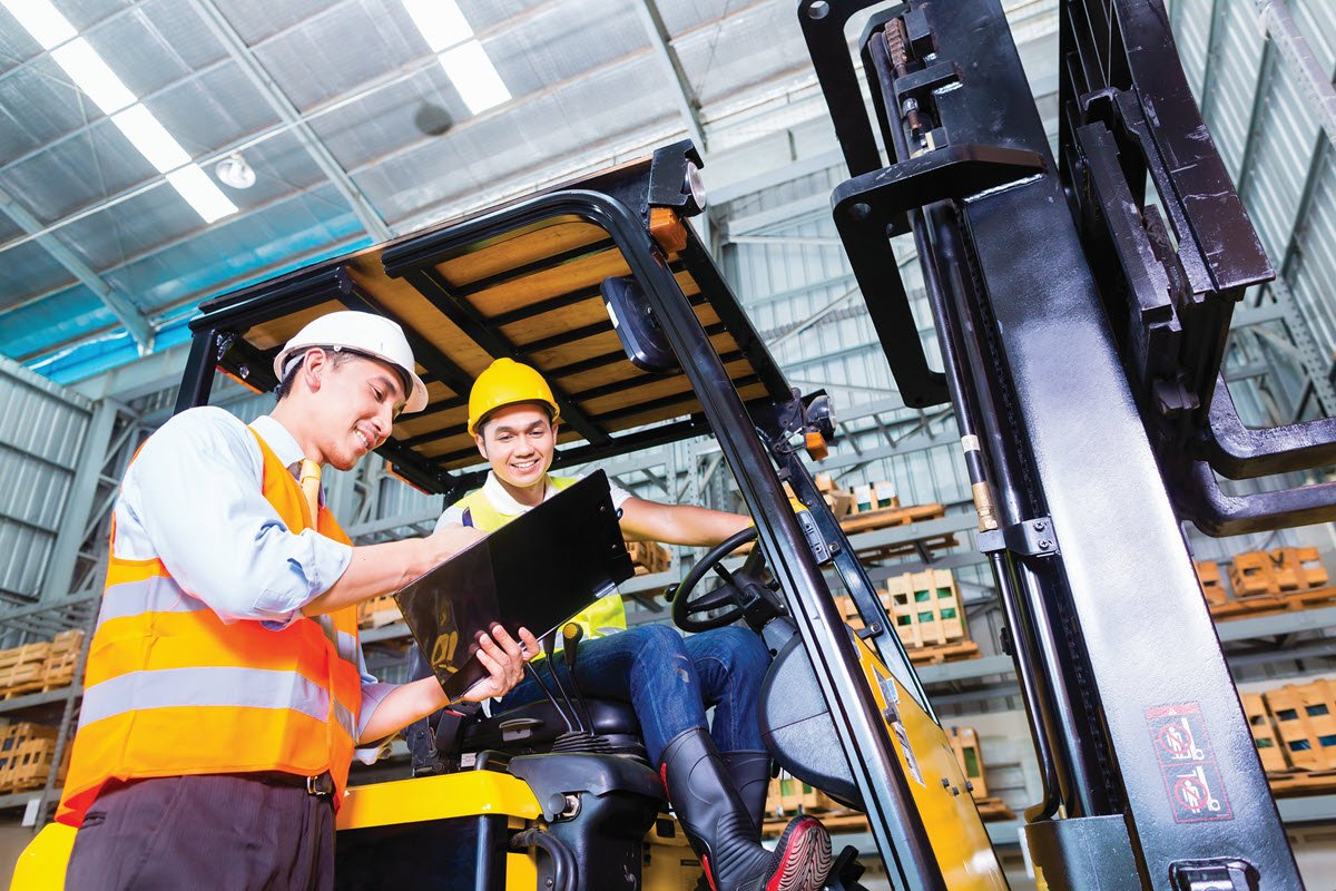 two employees talking near a forklift in a warehouse