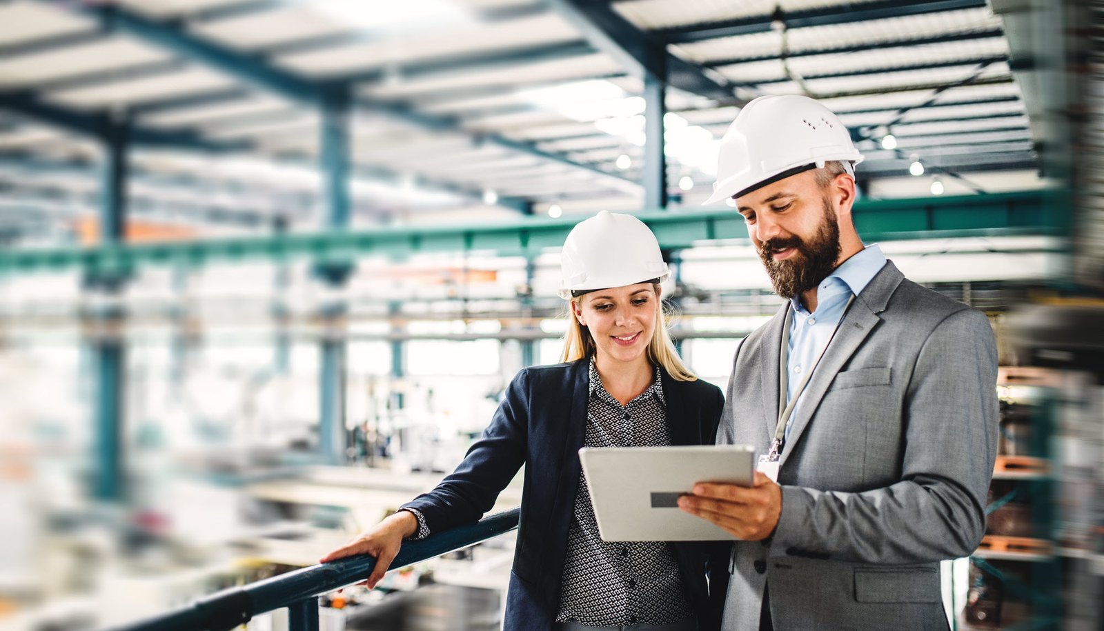 two people in hard hats standing in a factory