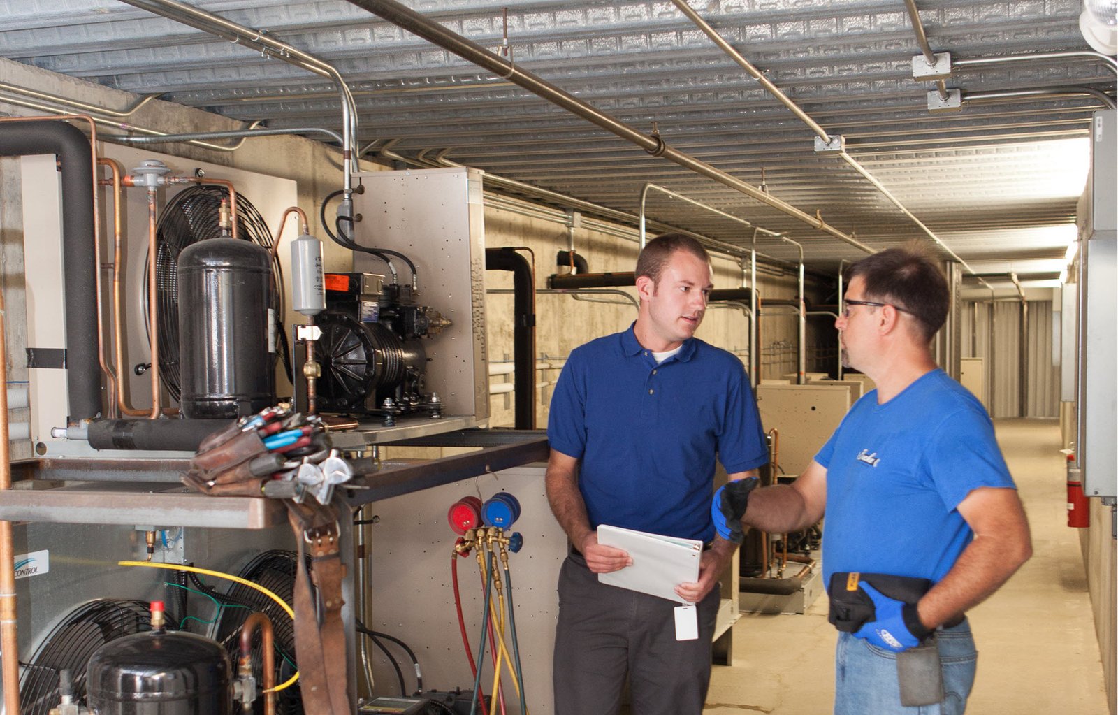two men talking next to mechanical equipment