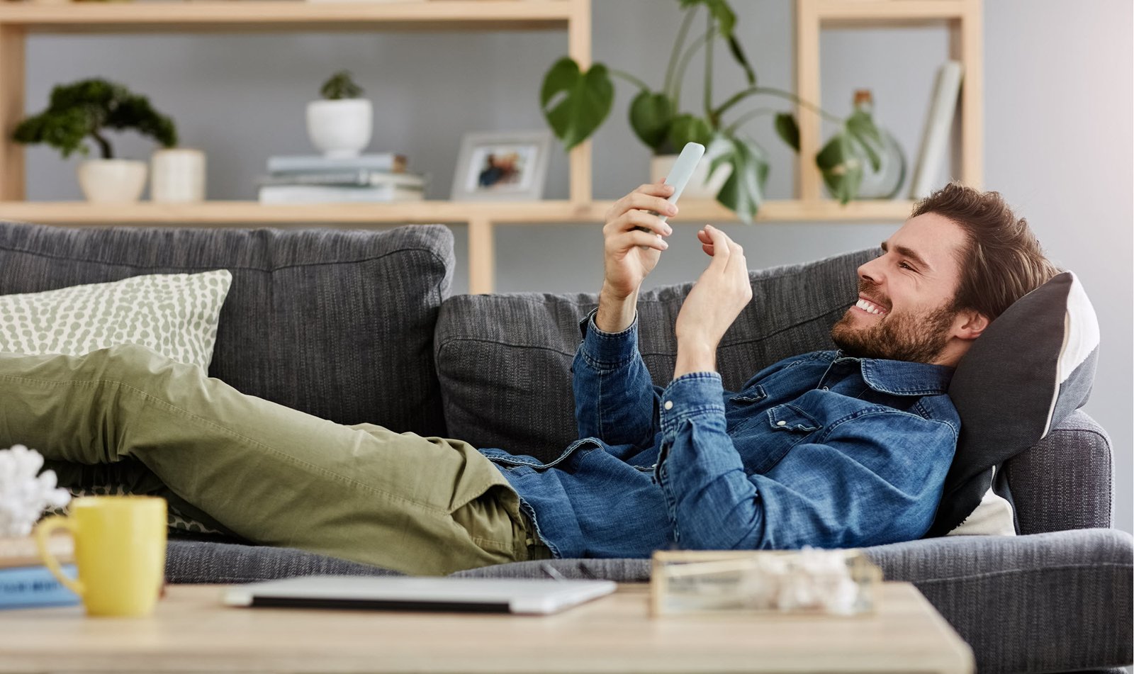 man lying on a couch looking at a phone